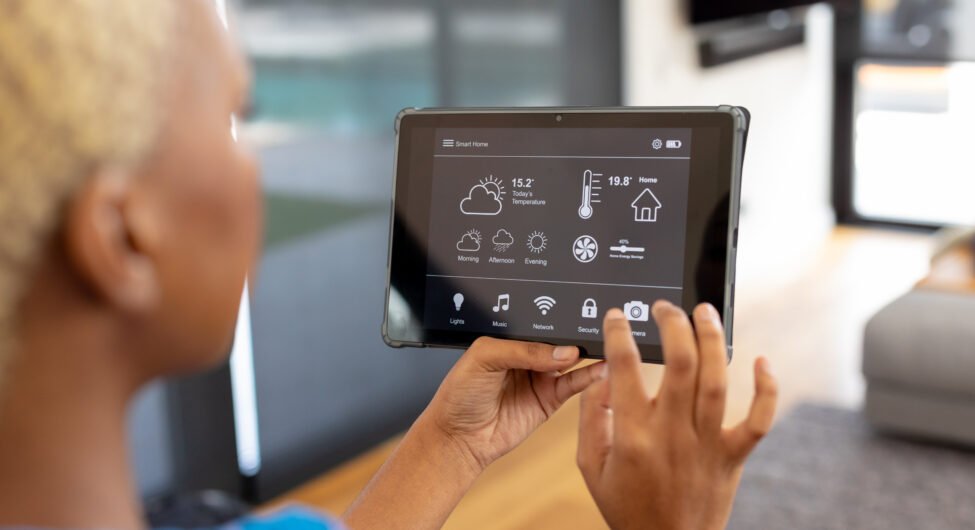 African american woman using tablet with smart home interface. Technology, home alone, domestic life and lifestyle concept.