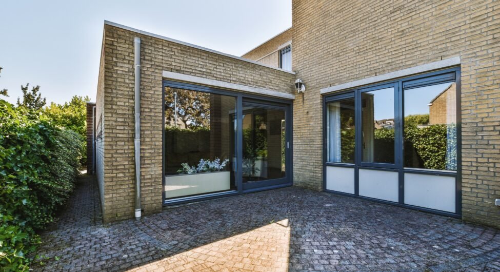 The front view of a brick building with signs,pavement and wooden doors lead to the apartment