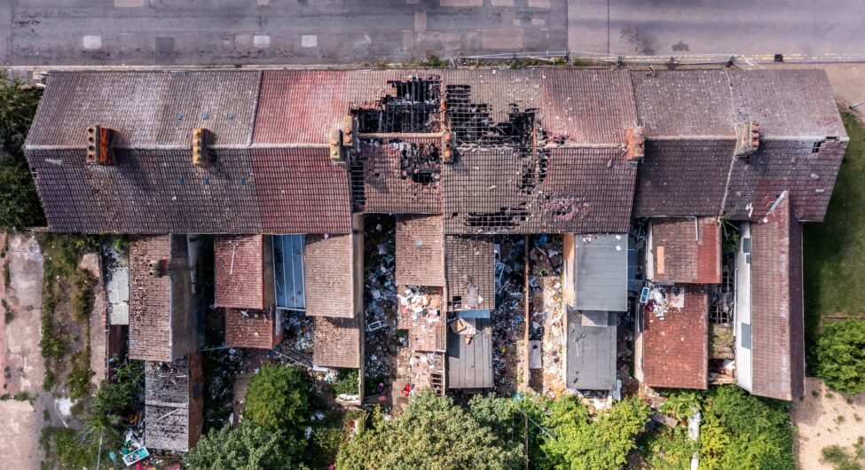 Aerial view directly above the roof of derelict terraced houses after a house fire