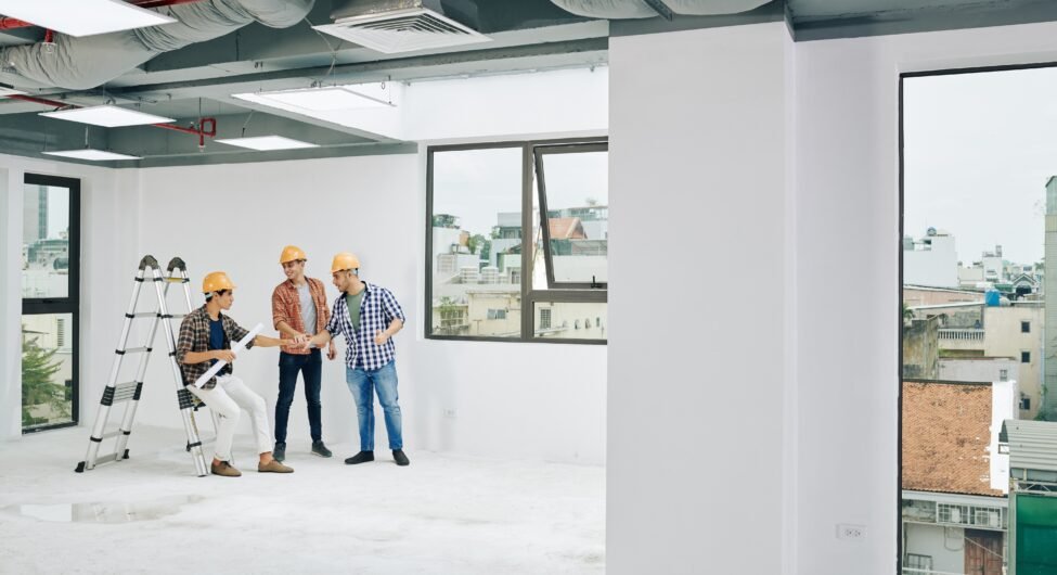 Young contractors stacking hands to support each other before starting work on big project