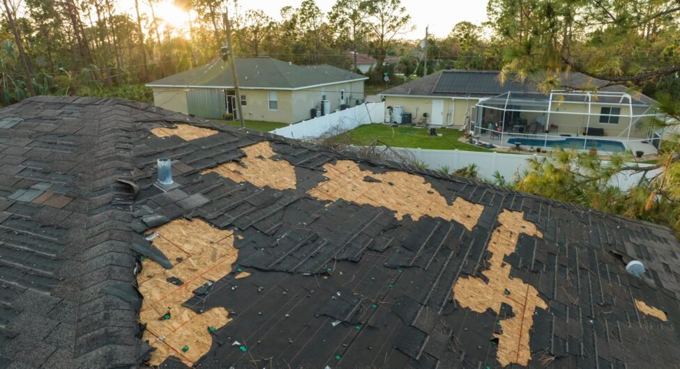 Damaged house roof with missing shingles after hurricane Ian in Florida