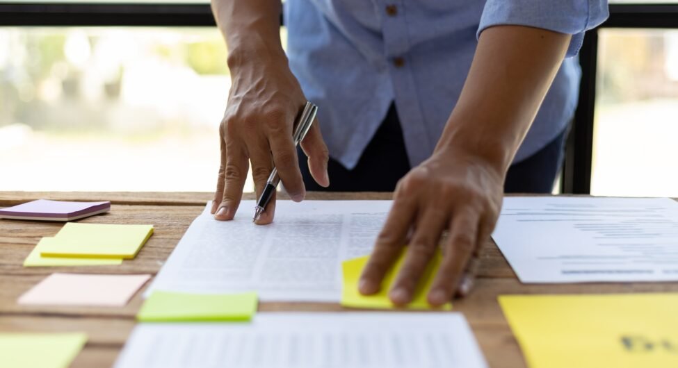 Man working on paperwork on desk, planning marketing business in office.
