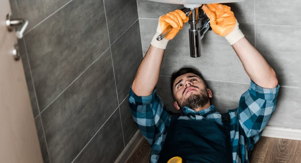 selective focus of repairman fixing water damage with wrench in bathroom