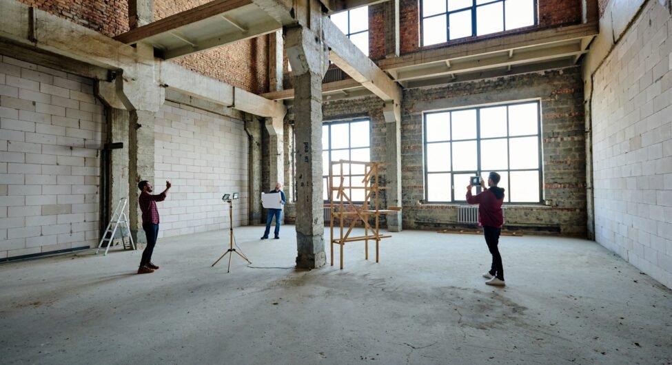 Two young contractors photographing unfinished structure inside building