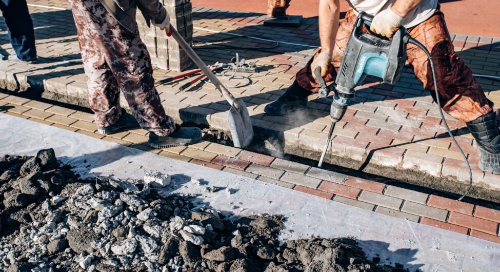Workers laid paving slabs. Two workers lay paving slabs.